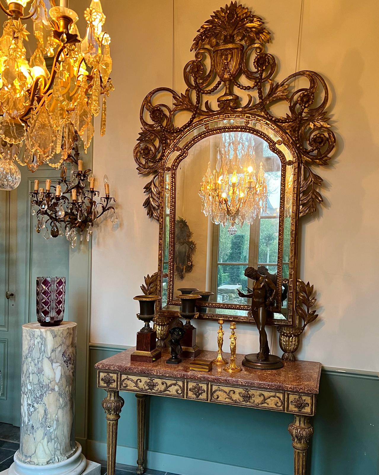 Giltwood mirror above a marble top console with bronzes and candlesticks